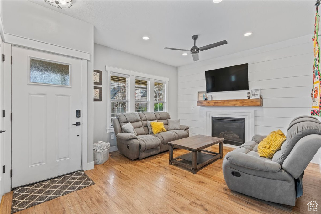 Living area with light wood finished floors, ceiling fan, recessed lighting, a glass covered fireplace, and baseboards