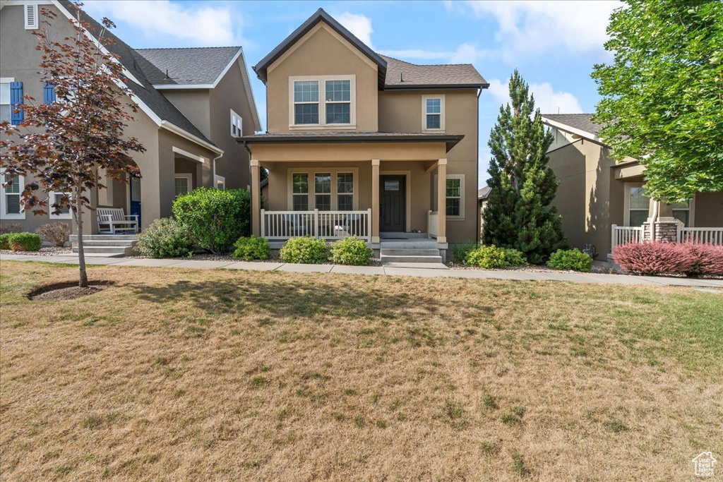 View of front of property featuring covered porch, stucco siding, and a front lawn