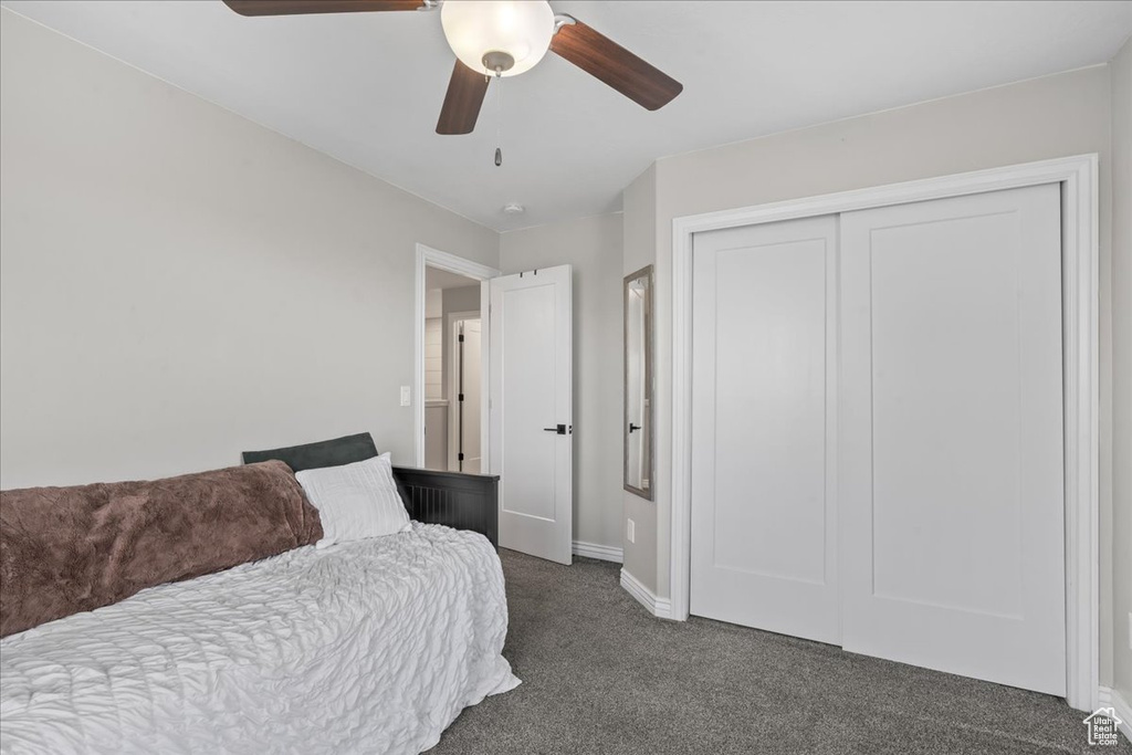 Bedroom with dark colored carpet, baseboards, a closet, and a ceiling fan