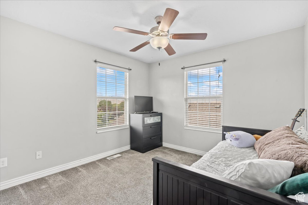 Carpeted bedroom featuring multiple windows, baseboards, and a ceiling fan