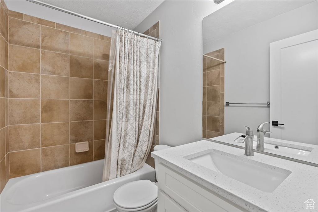 Bathroom featuring toilet, vanity, and shower / bath combo with shower curtain