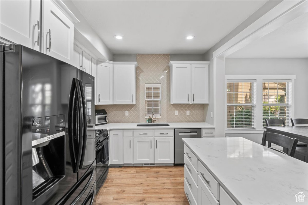 Kitchen featuring black appliances, white cabinetry, light wood finished floors, recessed lighting, and a sink