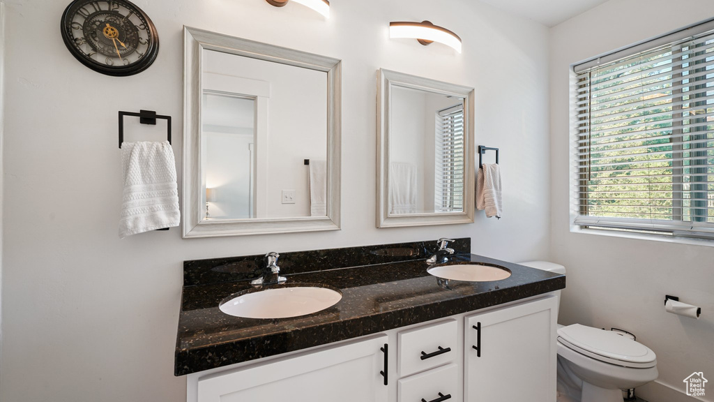 Bathroom featuring plenty of natural light, double vanity, and toilet