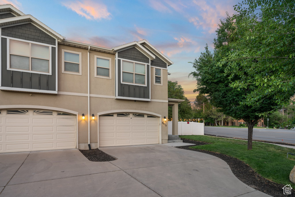 View of front of home featuring driveway, a garage, stucco siding, and a lawn