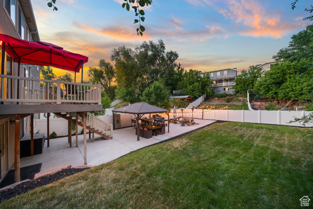 Yard at dusk with a patio, stairs, a gazebo, and a wooden deck