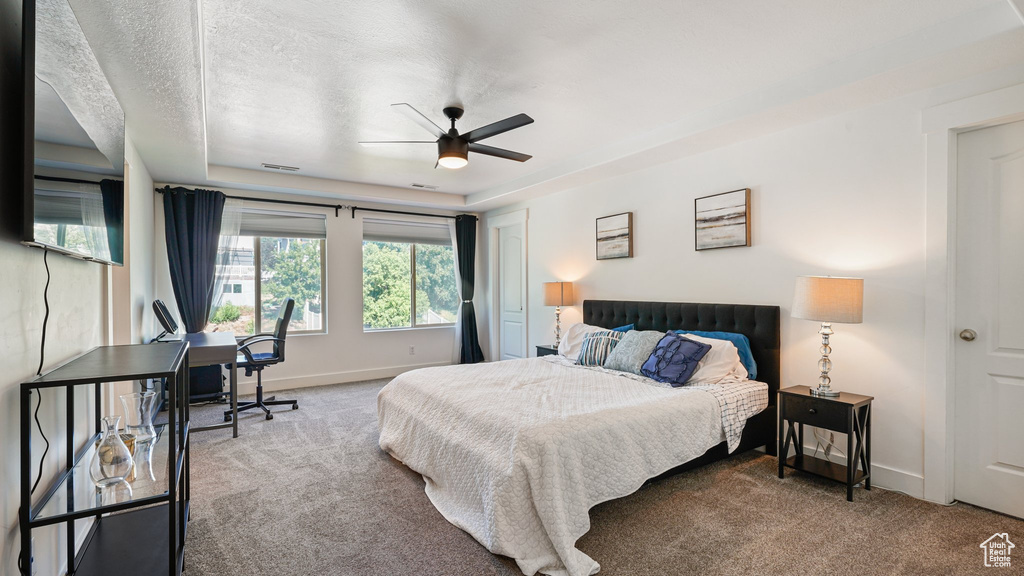 Bedroom featuring carpet flooring, baseboards, a ceiling fan, and a tray ceiling