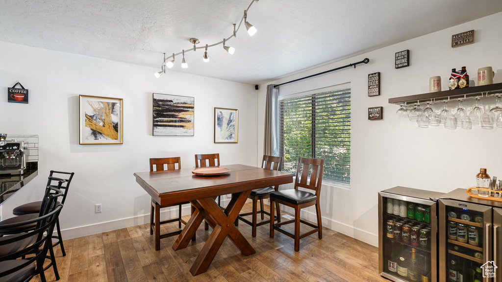 Dining area featuring a bar, baseboards, wood finished floors, and wine cooler