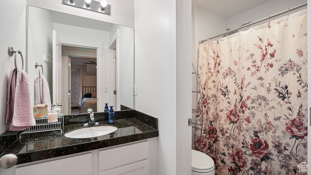 Ensuite bathroom featuring vanity, curtained shower, and toilet