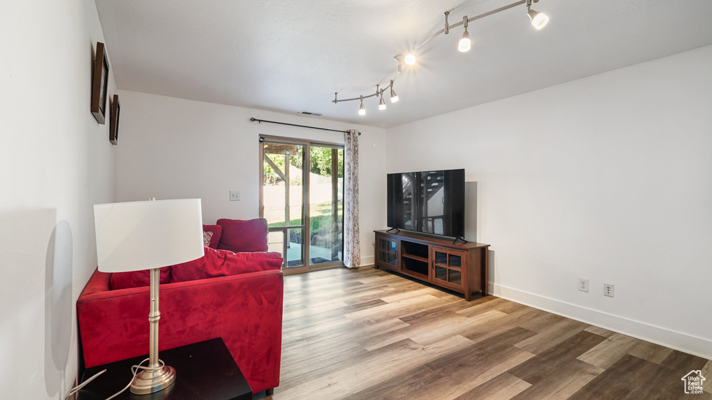 Living area featuring wood finished floors, baseboards, and rail lighting
