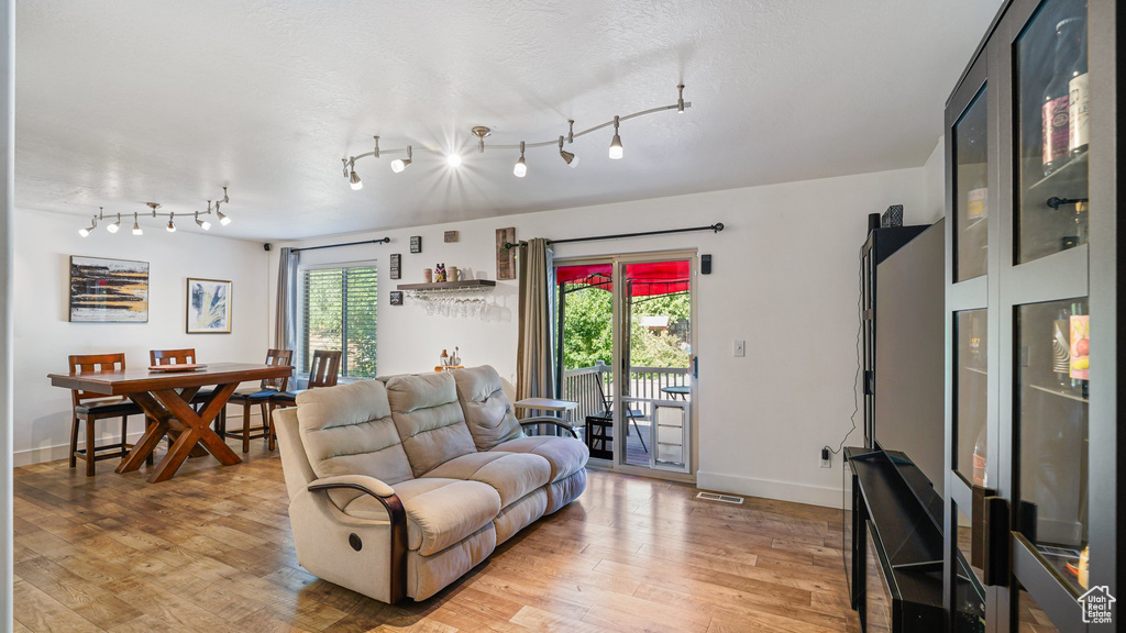 Living area with light wood-style floors, track lighting, and baseboards
