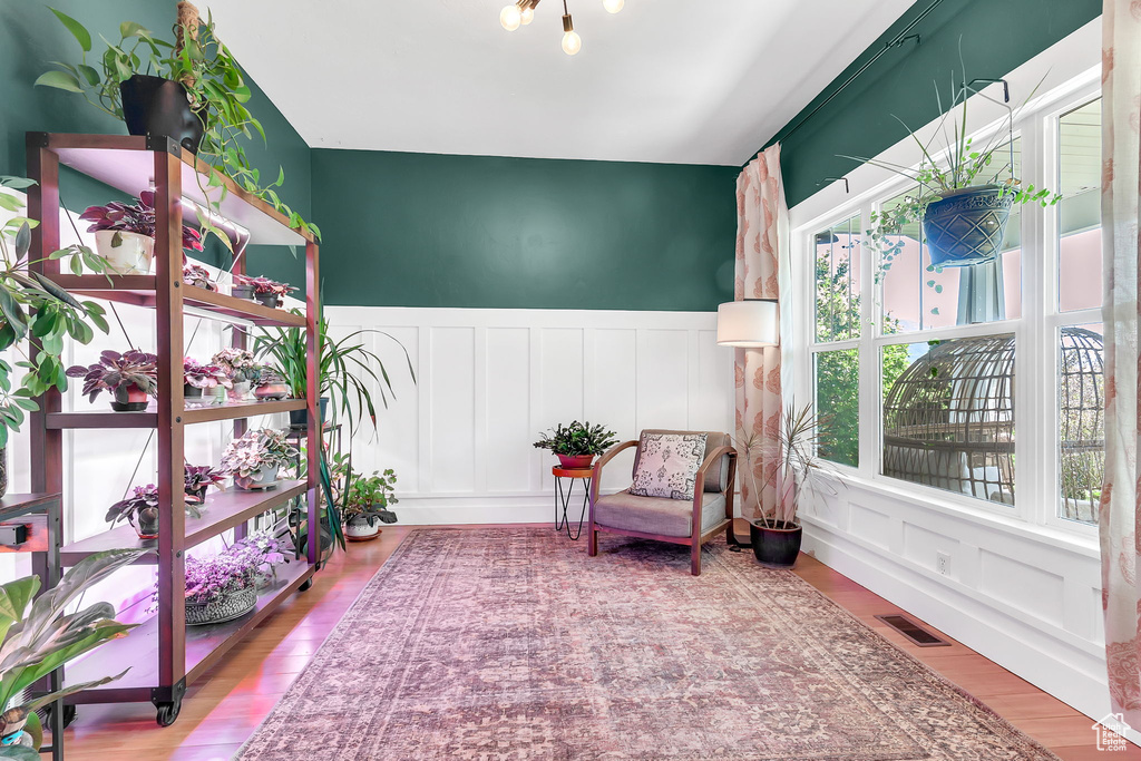 Sitting room with plenty of natural light, a decorative wall, wainscoting, and wood finished floors