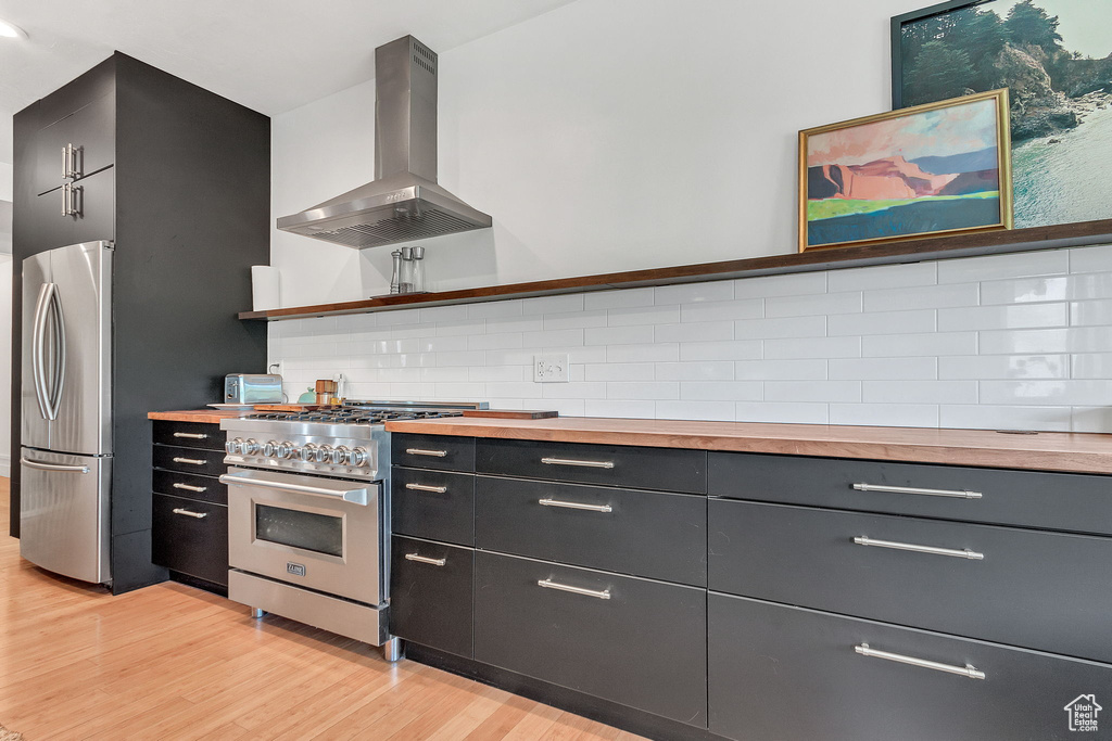 Kitchen with island range hood, appliances with stainless steel finishes, butcher block countertops, light wood-type flooring, and open shelves