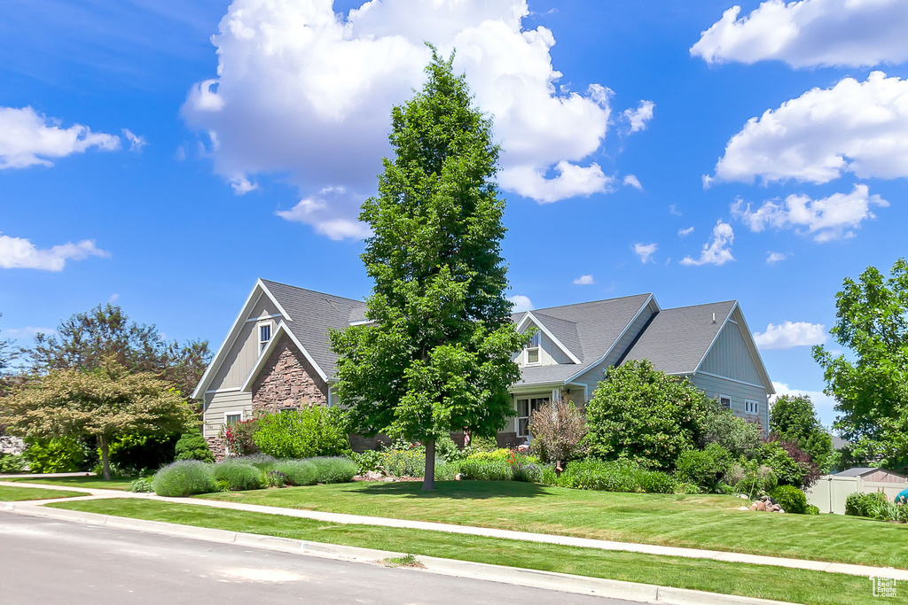 View of front facade featuring board and batten siding, a front lawn, and stone siding