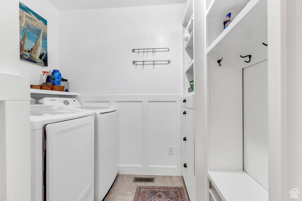 Laundry area featuring washing machine and clothes dryer, a wainscoted wall, and a decorative wall