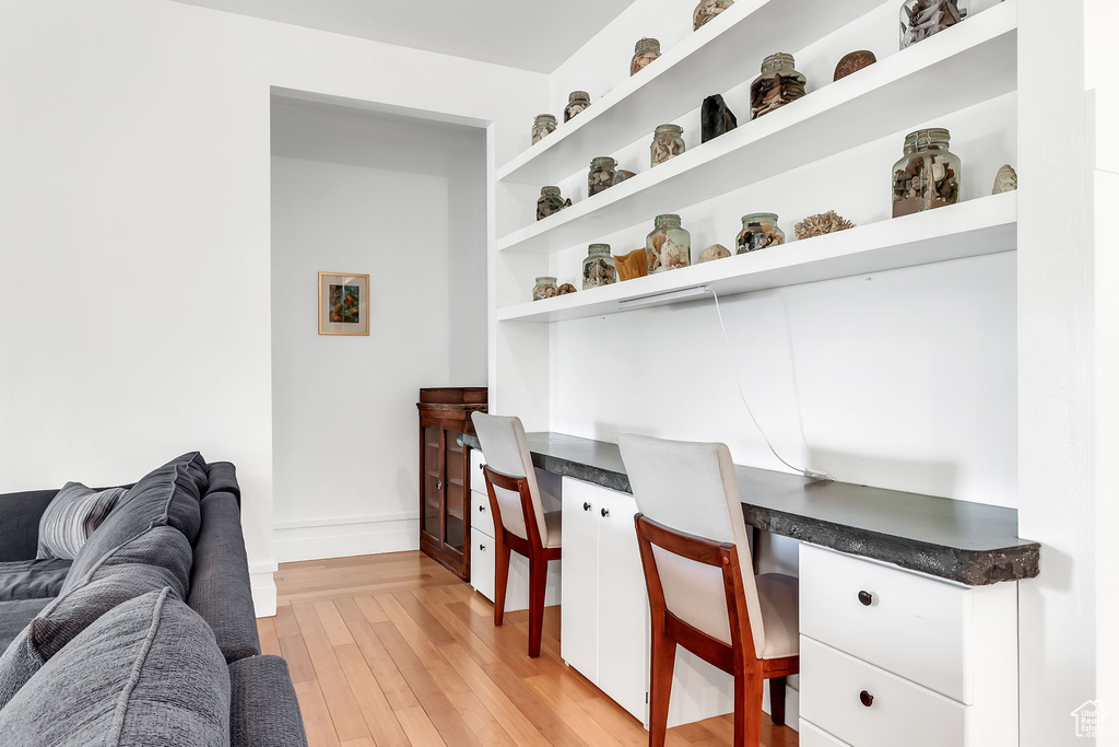 Office space featuring built in desk, light wood finished floors, and baseboards