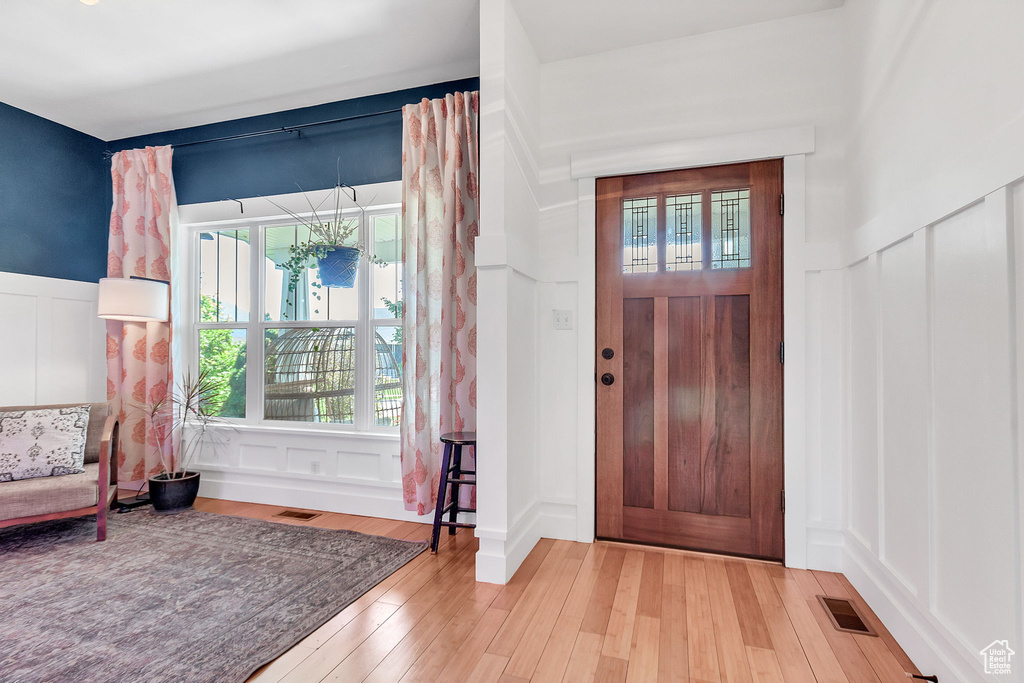 Foyer featuring a decorative wall, wood finished floors, and a wainscoted wall