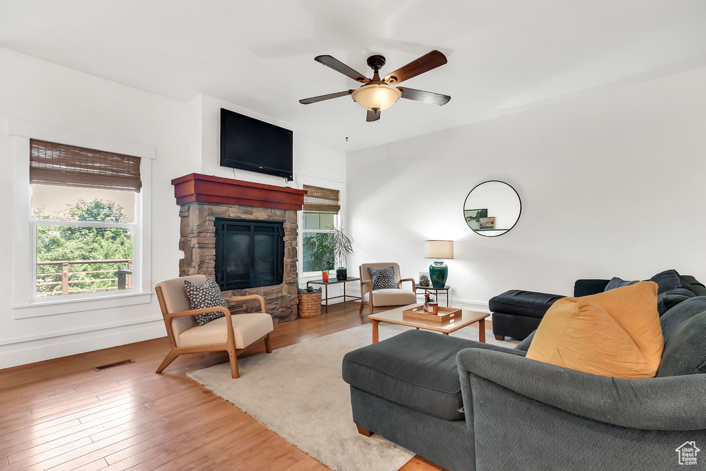 Living room featuring a ceiling fan, wood-type flooring, a fireplace, and baseboards