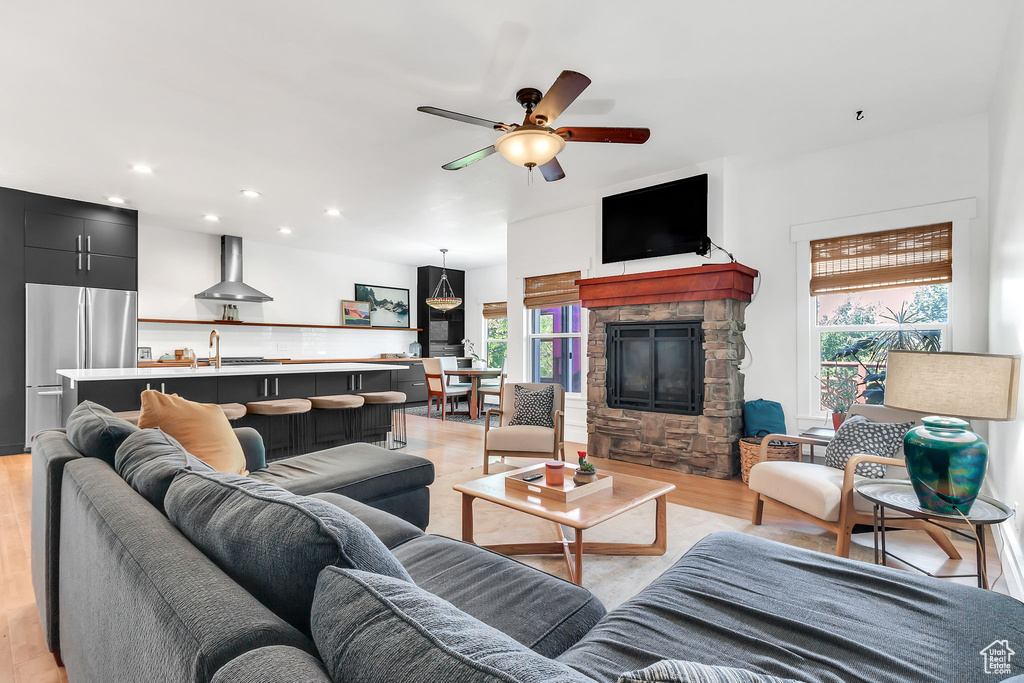 Living area featuring a ceiling fan, light wood-style floors, recessed lighting, and a stone fireplace