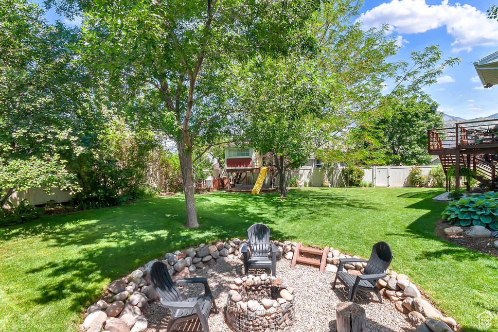 View of yard with an outdoor fire pit, a wooden deck, and stairway