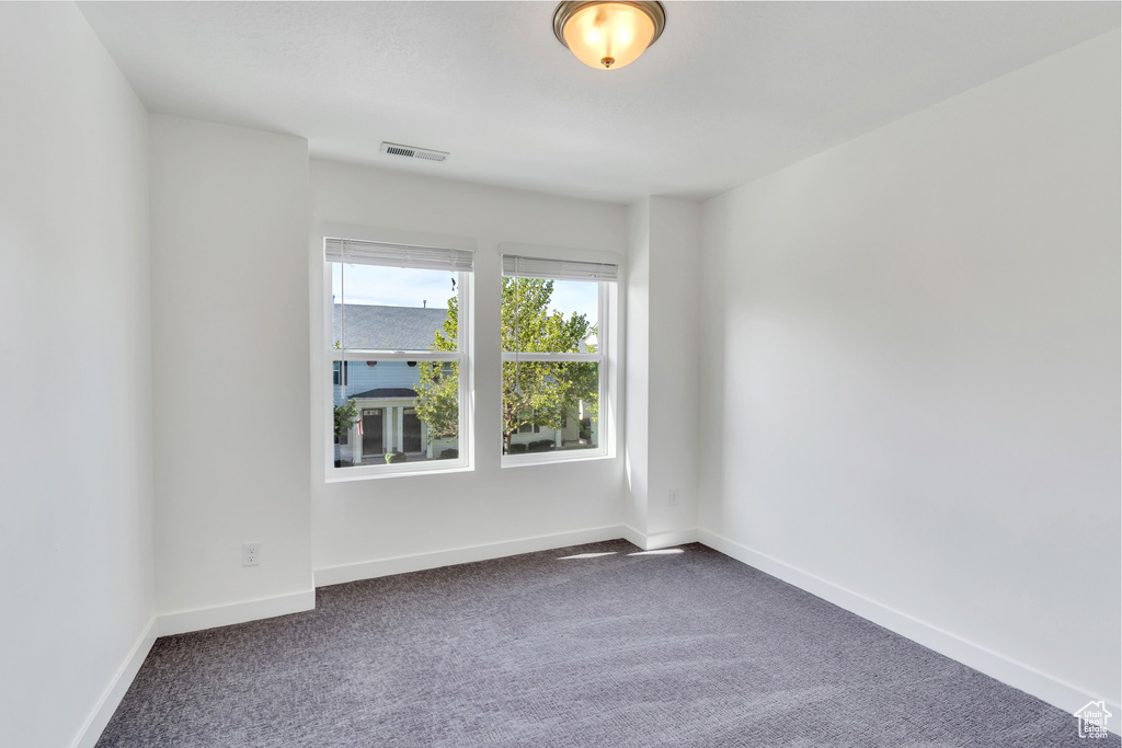 Unfurnished room with dark carpet and baseboards