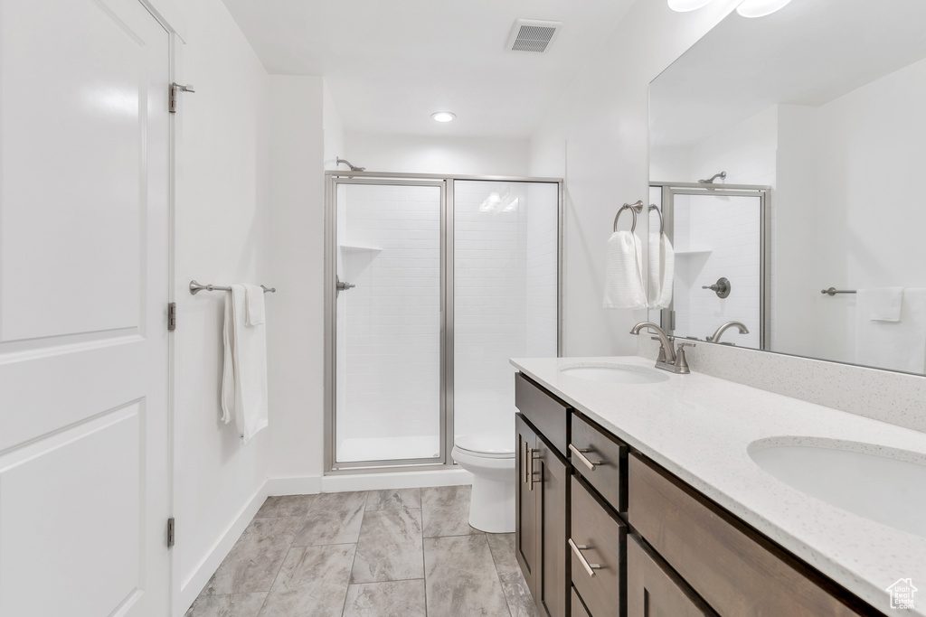 Full bath featuring a shower stall, toilet, double vanity, and recessed lighting