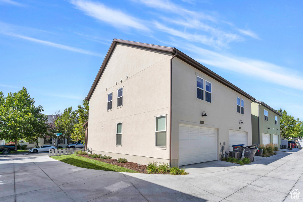 View of property exterior with stucco siding, an attached garage, and concrete driveway