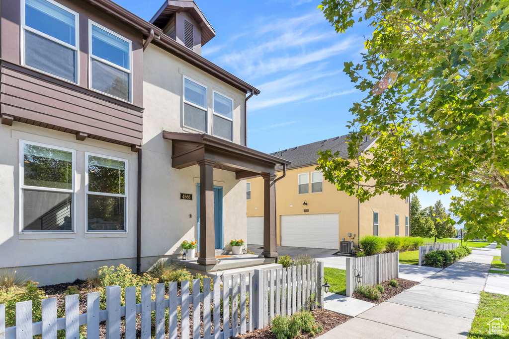 Townhome / multi-family property featuring a garage, stucco siding, a fenced front yard, and driveway