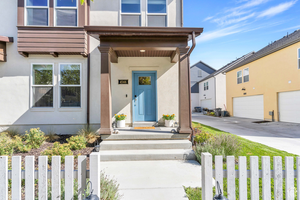 Property entrance featuring stucco siding, an attached garage, and driveway