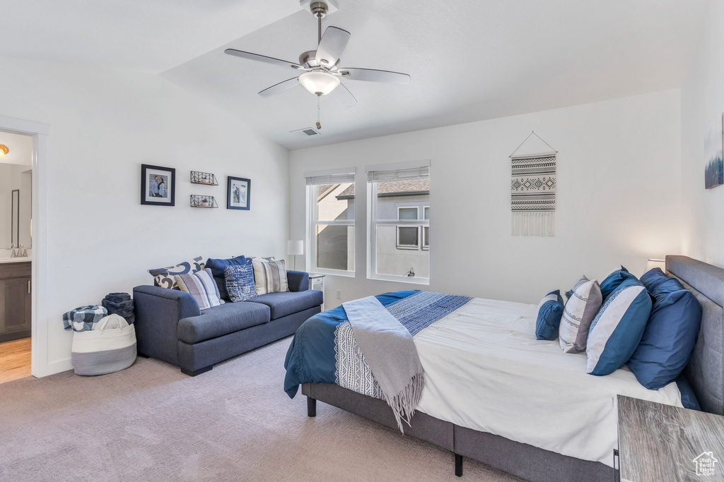 Bedroom with vaulted ceiling, carpet floors, ceiling fan, and connected bathroom