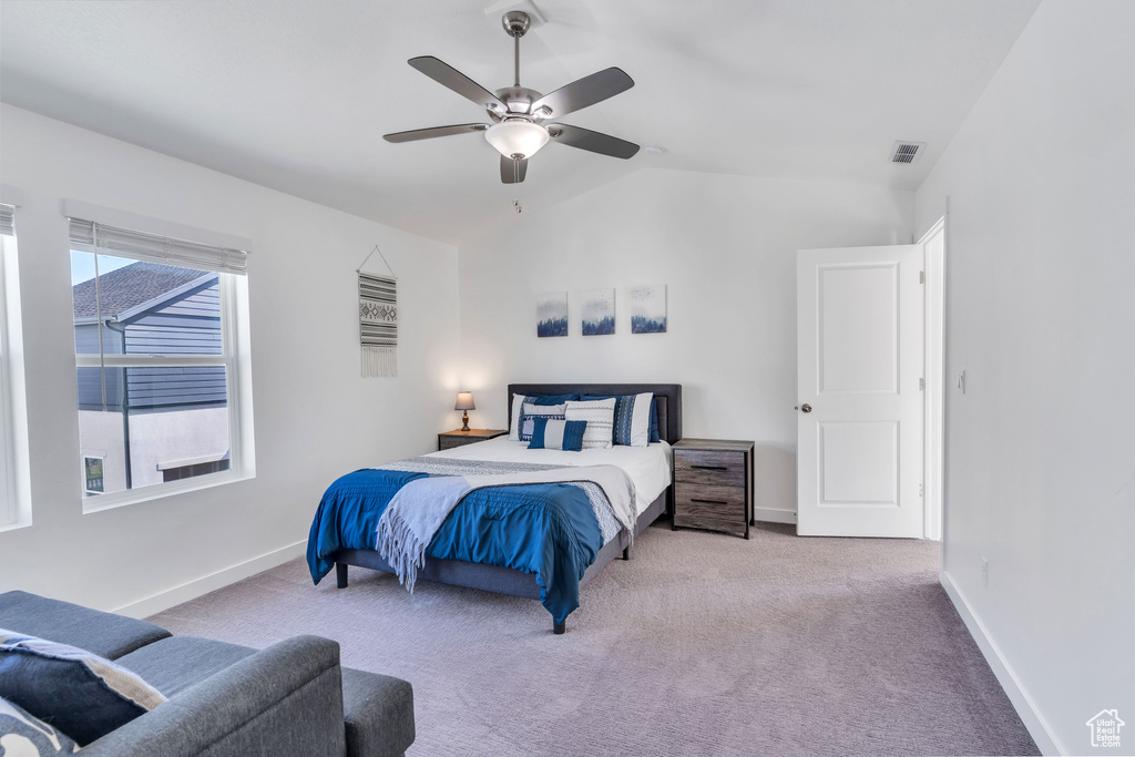 Carpeted bedroom featuring lofted ceiling, baseboards, and a ceiling fan