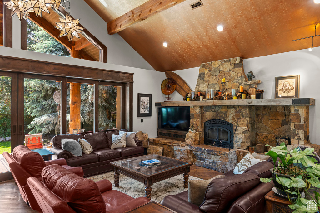 Living room with high vaulted ceiling, wood finished floors, french doors, beam ceiling, and a stone fireplace