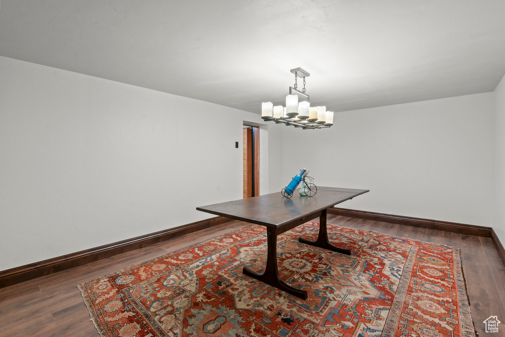 Unfurnished dining area with a chandelier, baseboards, and wood finished floors