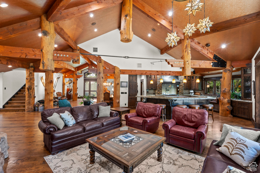 Living room with wood finished floors, beamed ceiling, stairs, recessed lighting, and decorative columns