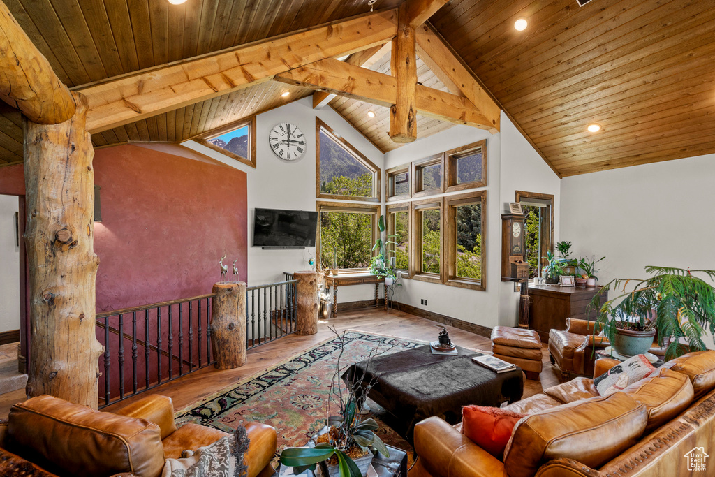 Living room with wooden ceiling with exposed beams, wood finished floors, high vaulted ceiling, recessed lighting, and baseboards