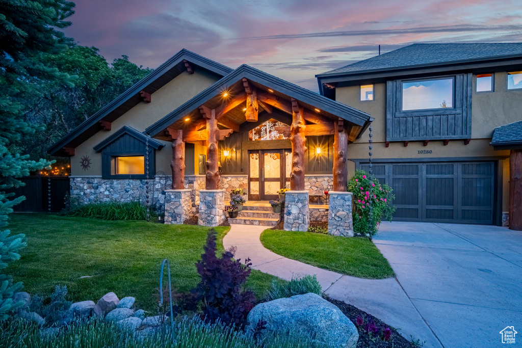 View of front facade with an attached garage, stucco siding, stone siding, and concrete driveway