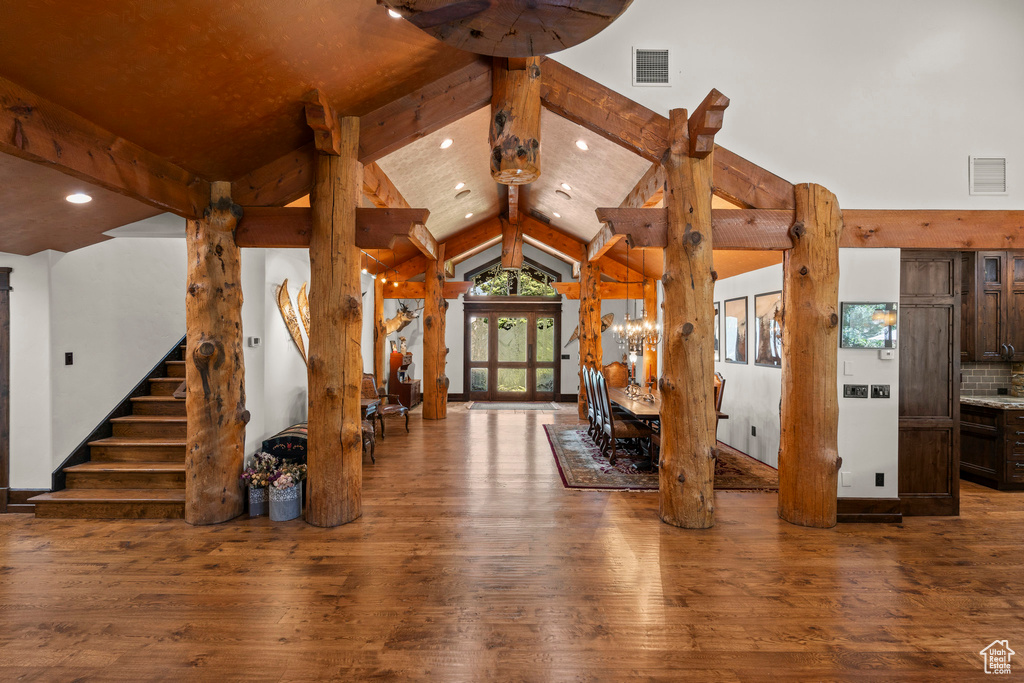 Unfurnished living room featuring wood-type flooring, beamed ceiling, recessed lighting, stairway, and high vaulted ceiling