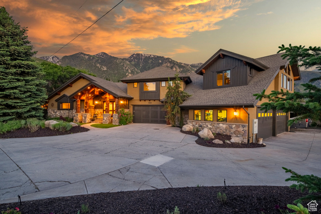 View of front of house with an attached garage, stone siding, driveway, and a mountain view