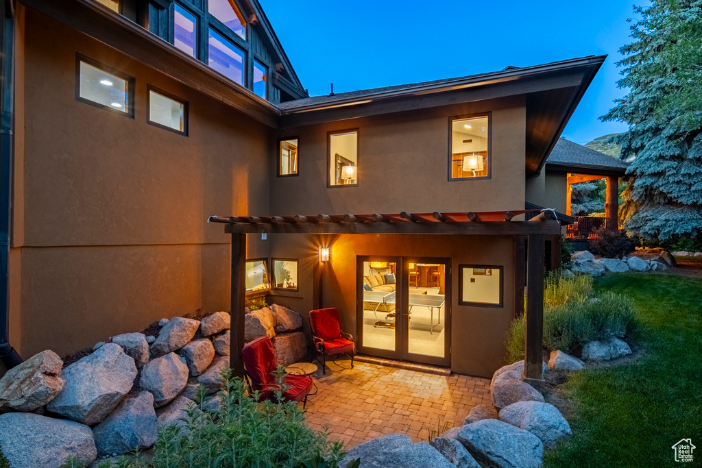 Rear view of property featuring stucco siding, a pergola, french doors, and a patio