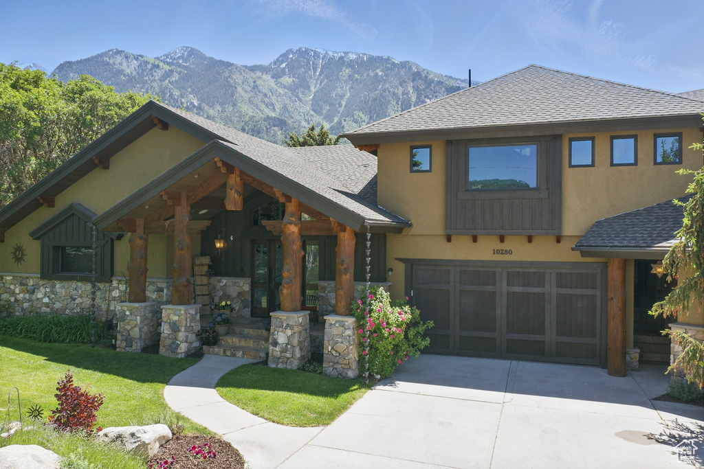 View of front of property featuring an attached garage, a mountain view, concrete driveway, and stucco siding