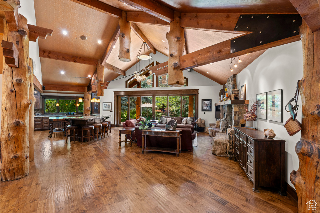 Living room featuring wood-type flooring, beamed ceiling, high vaulted ceiling, a fireplace, and recessed lighting