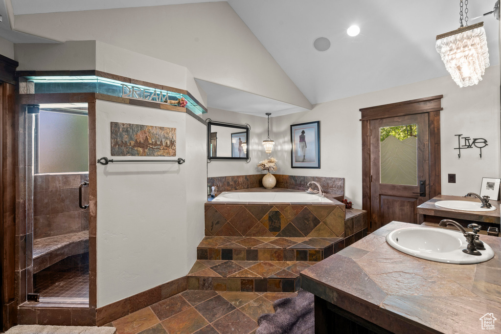 Full bathroom with stone tile flooring, a garden tub, vanity, a stall shower, and baseboards