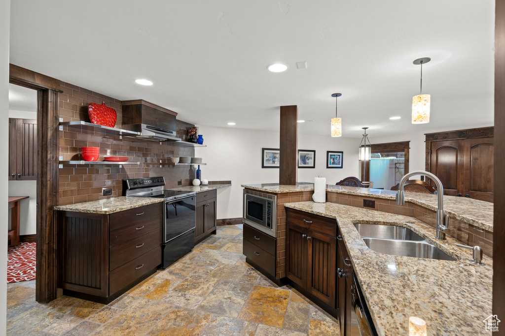 Kitchen featuring black electric range oven, a sink, stone tile floors, stainless steel microwave, and tasteful backsplash