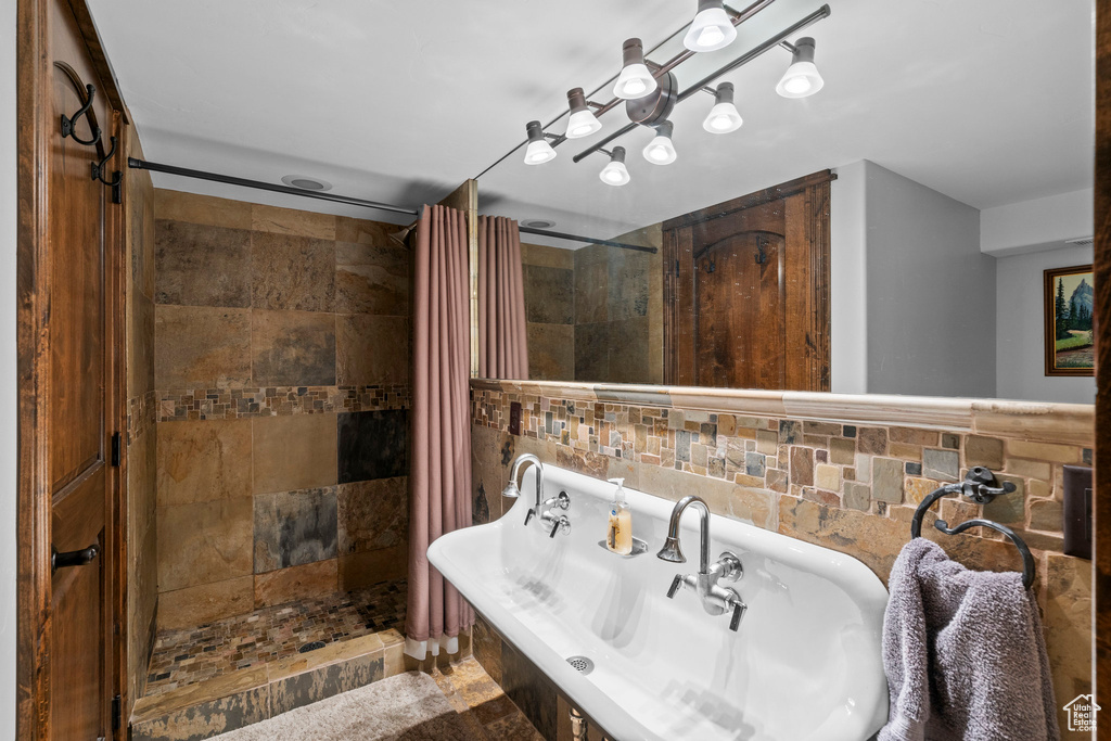 Full bathroom featuring tiled shower and tile walls
