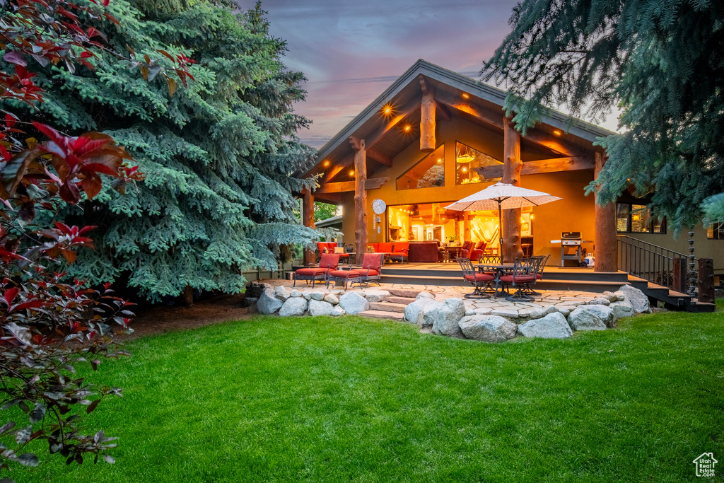Back of house at dusk featuring a yard, a patio area, an outdoor living space, and outdoor dining space