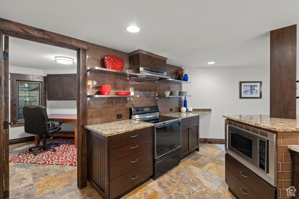 Kitchen with black electric range, stone tile floors, stainless steel microwave, baseboards, and under cabinet range hood