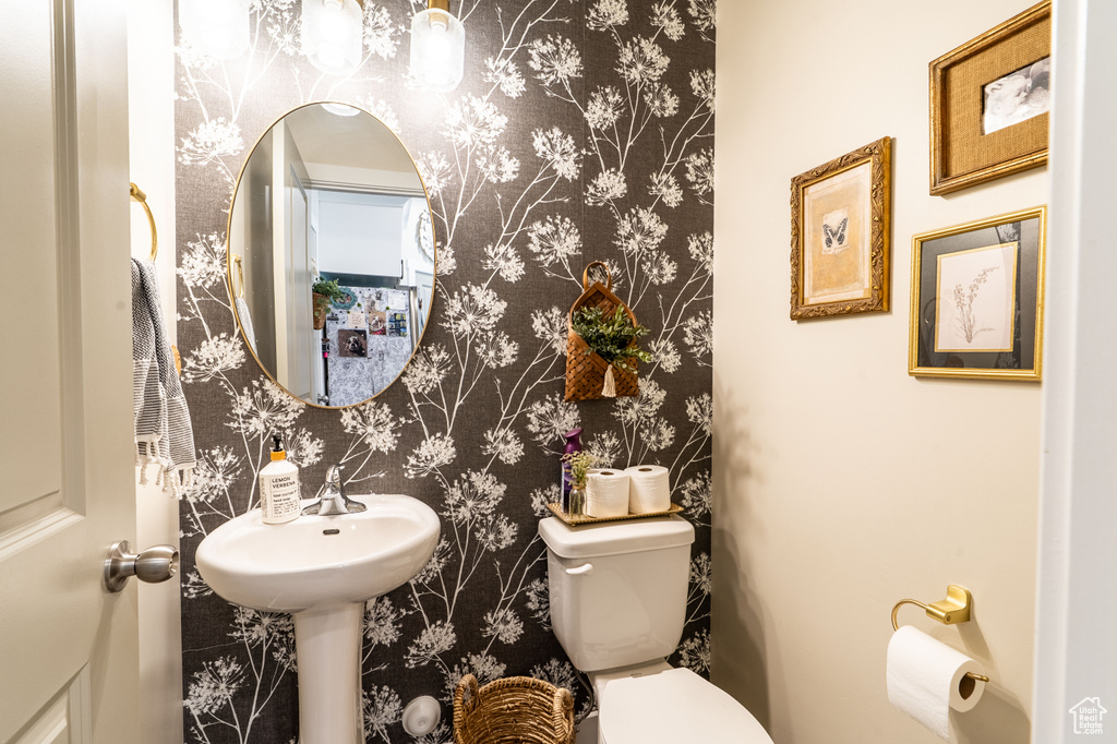 Bathroom featuring wallpapered walls and toilet