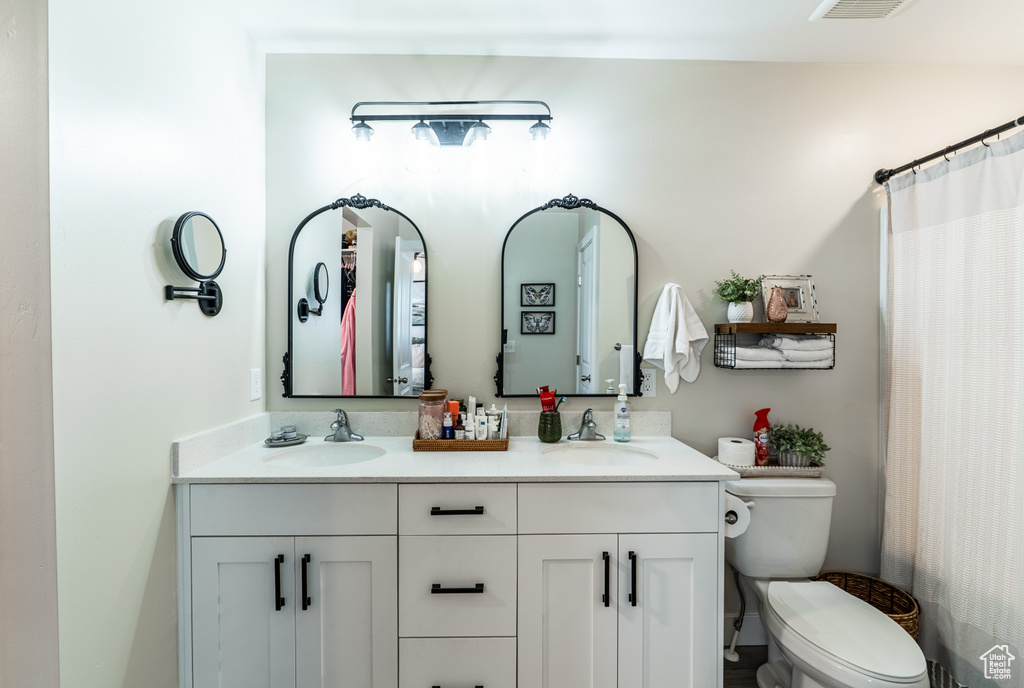 Full bath featuring double vanity, toilet, and a shower with shower curtain