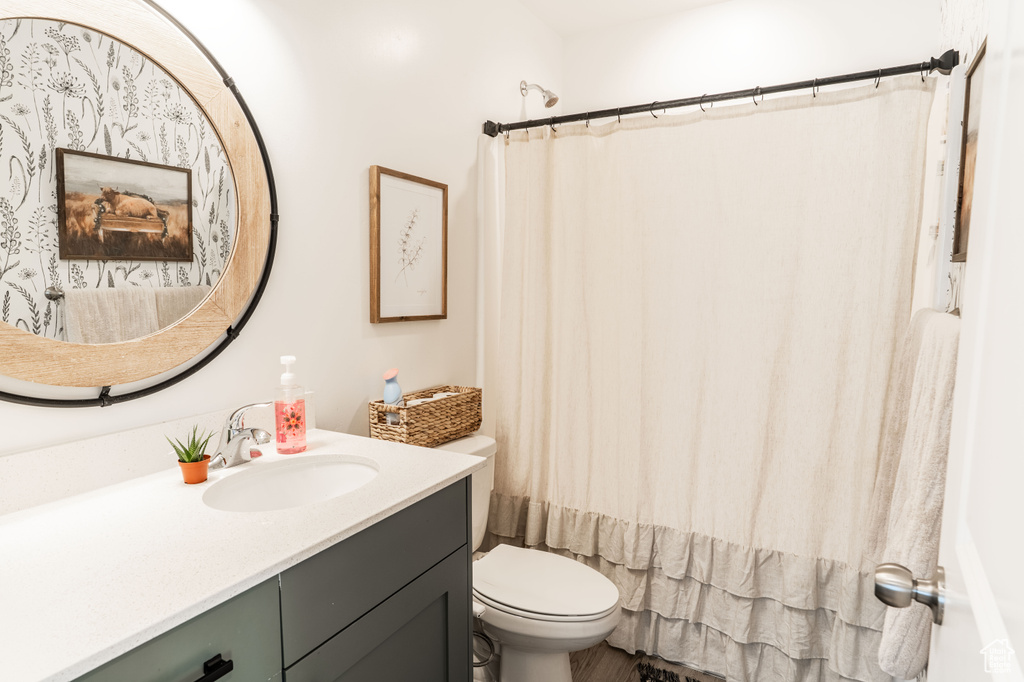Bathroom with vanity, toilet, and shower / tub combo with curtain