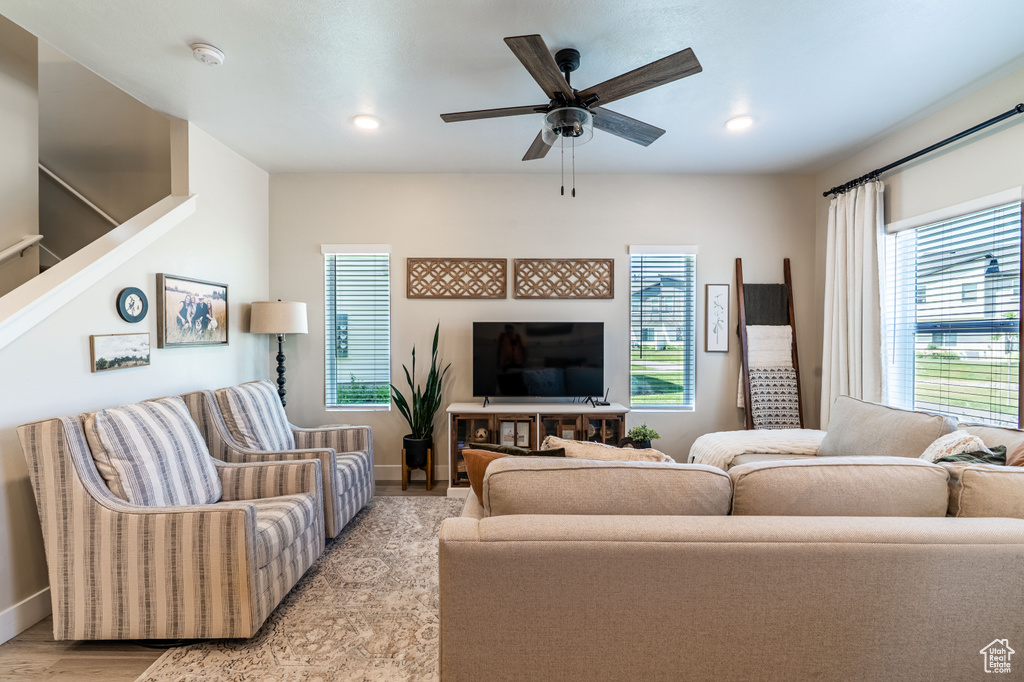 Living area featuring a ceiling fan, baseboards, light wood-type flooring, recessed lighting, and stairway