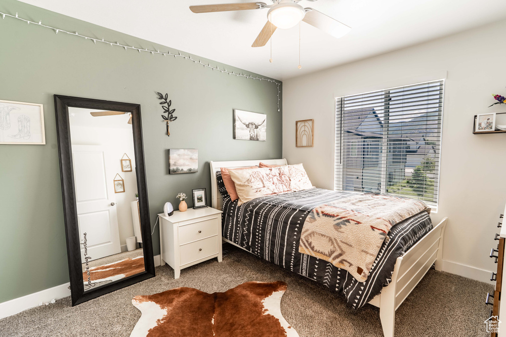 Carpeted bedroom with a ceiling fan and baseboards